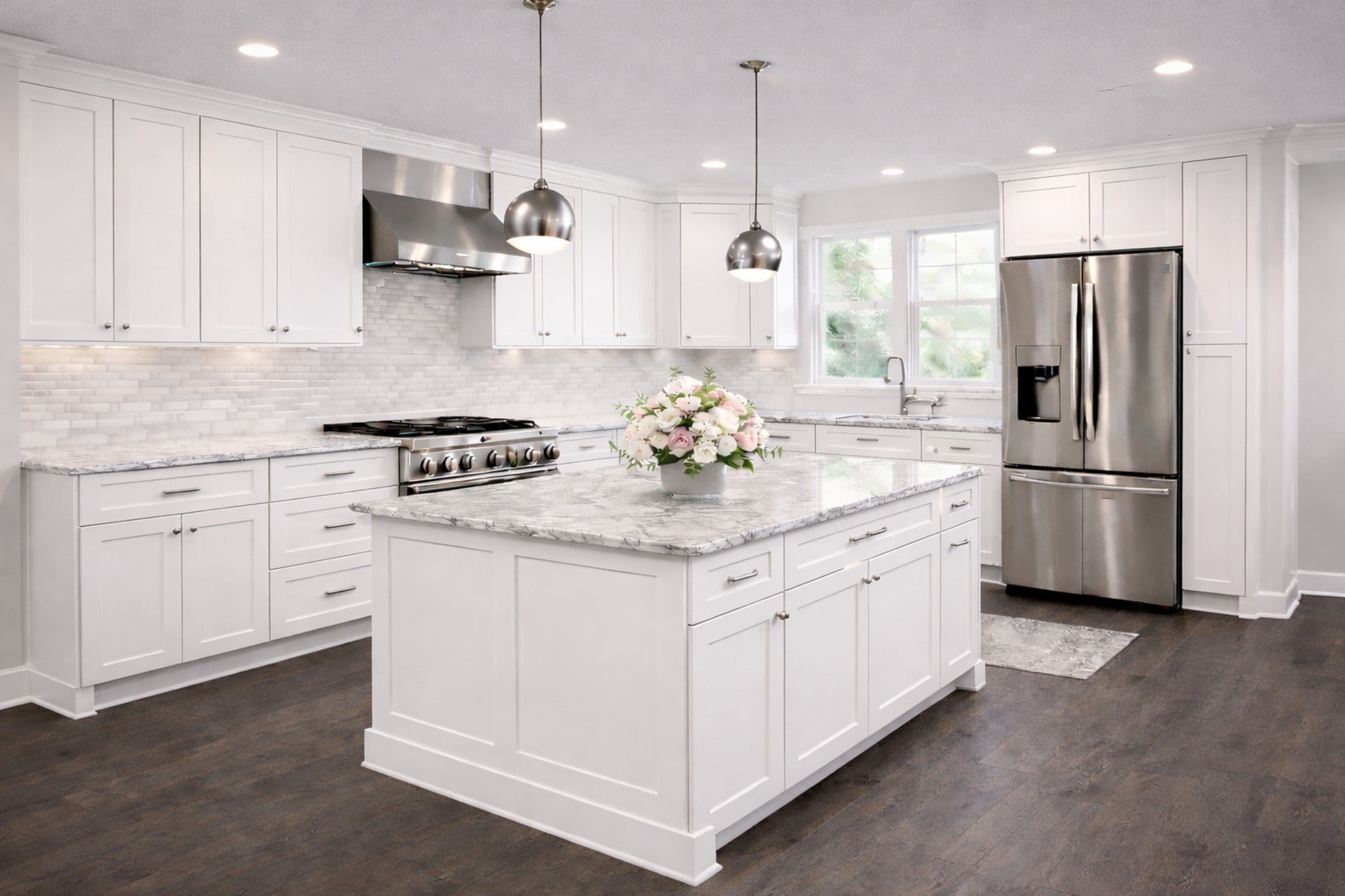 White shaker L-shaped kitchen with large island, marble countertops, and stainless appliances