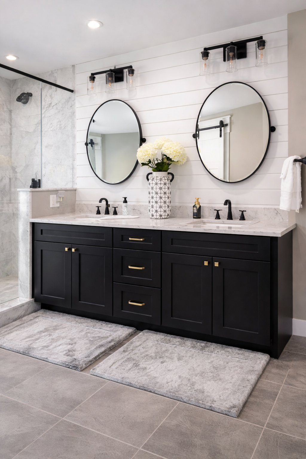 A black shaker bathroom vanity in a modern bathroom design with glass door shower, dual sinks and round, black-frame mirrors